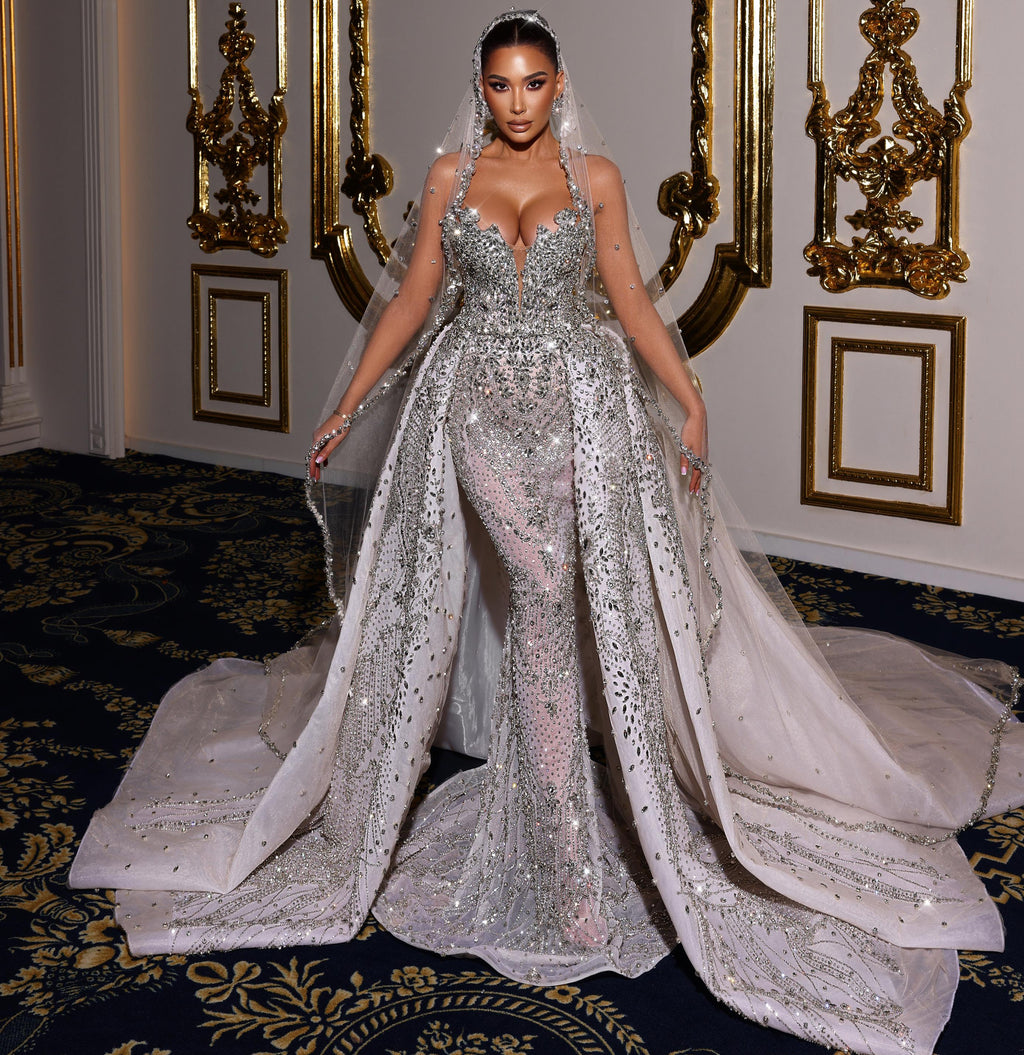 Woman in a sparkling silver wedding gown standing in an ornate room.
