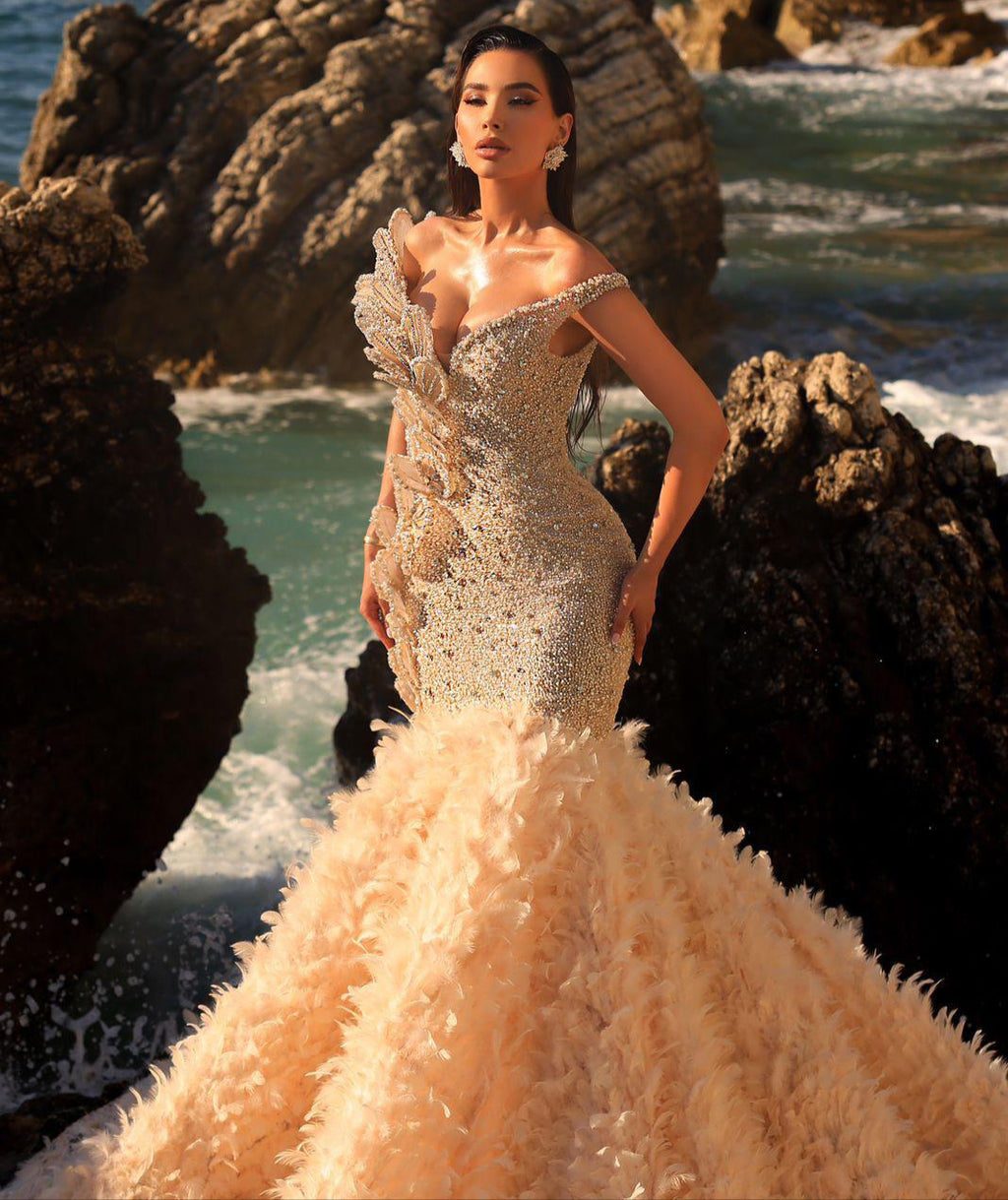 Woman in a glamorous gown standing on rocky coastal terrain