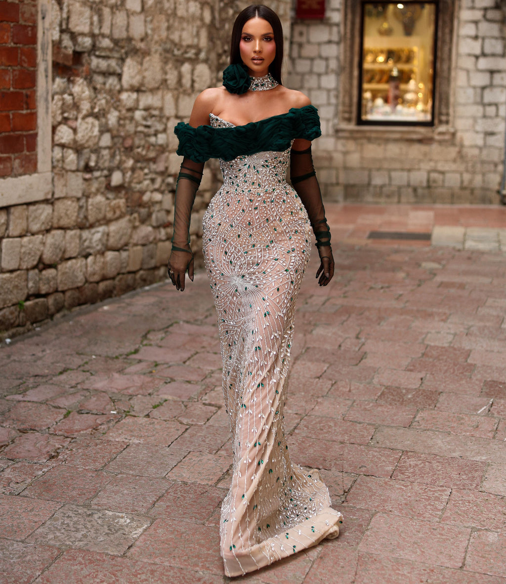 Woman in a green and white dress walking along a stone alleyway.