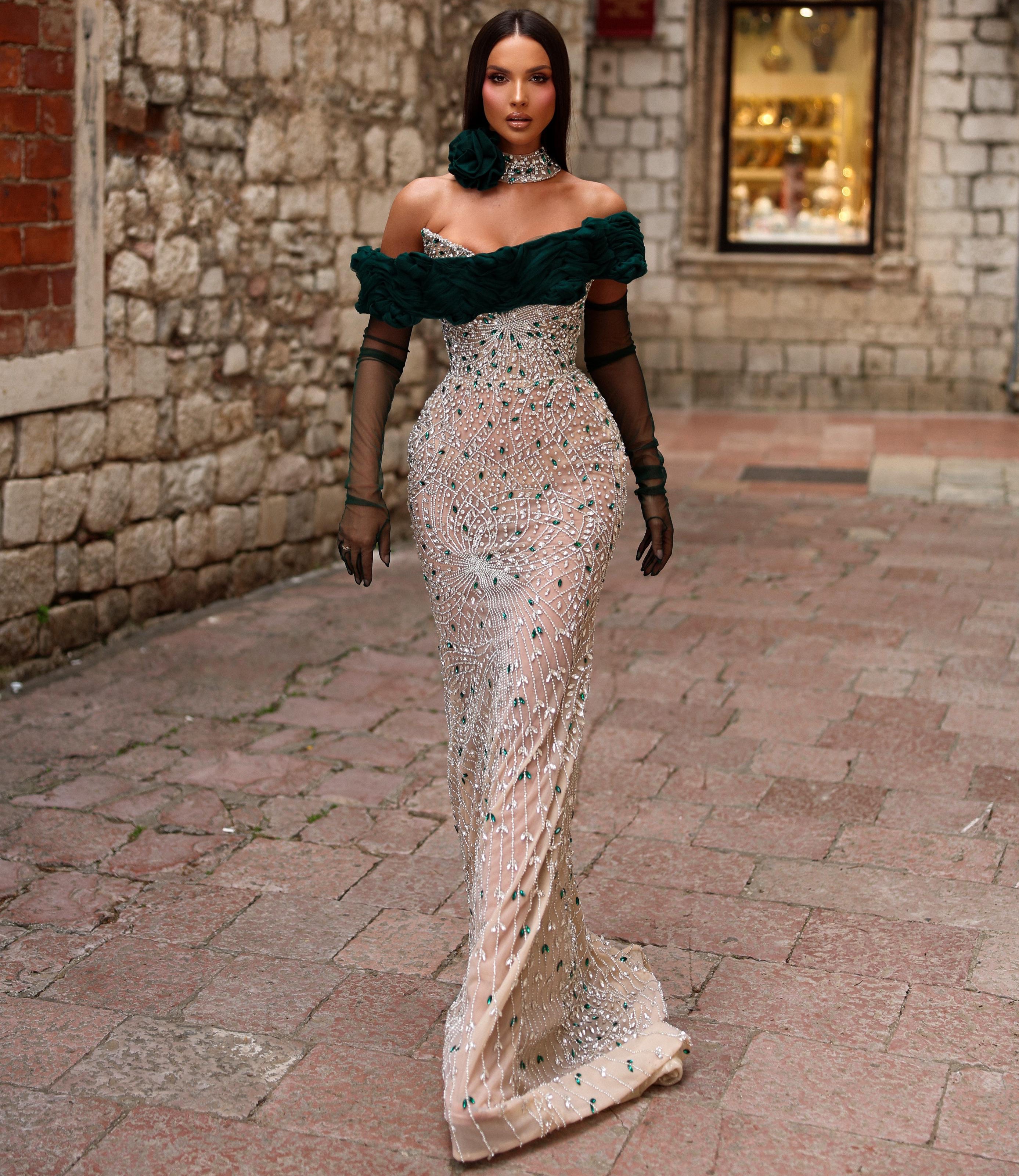 Woman in a green and white dress walking along a stone alleyway.