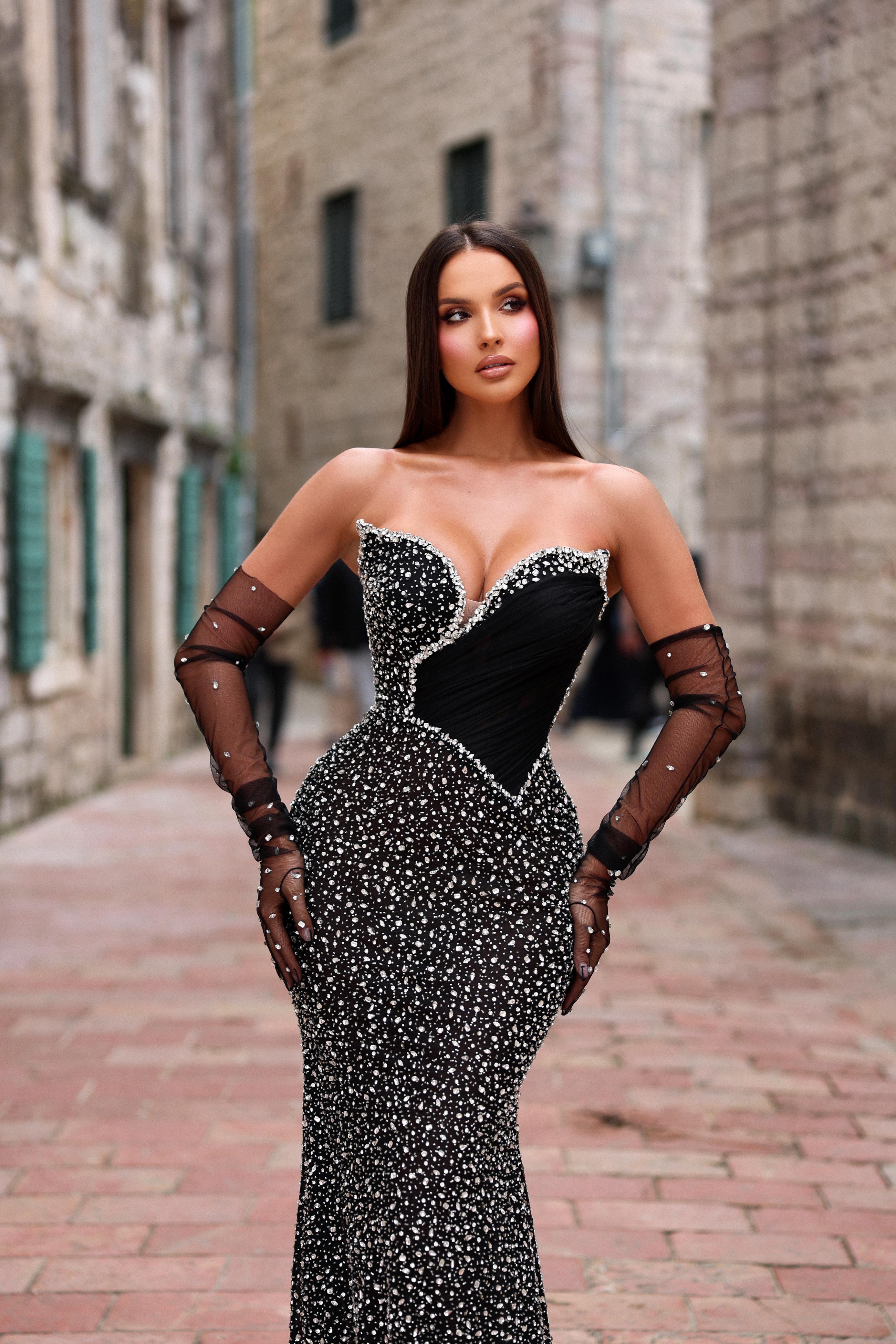 Woman in a black and white dress with sheer sleeves on a street.