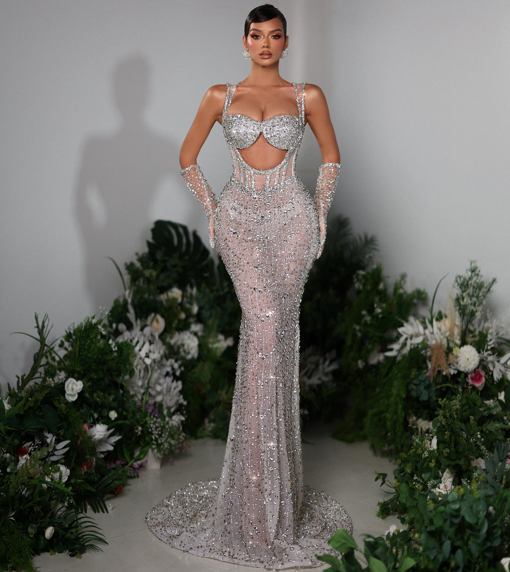 Woman in a sparkling evening gown standing in front of floral decorations.