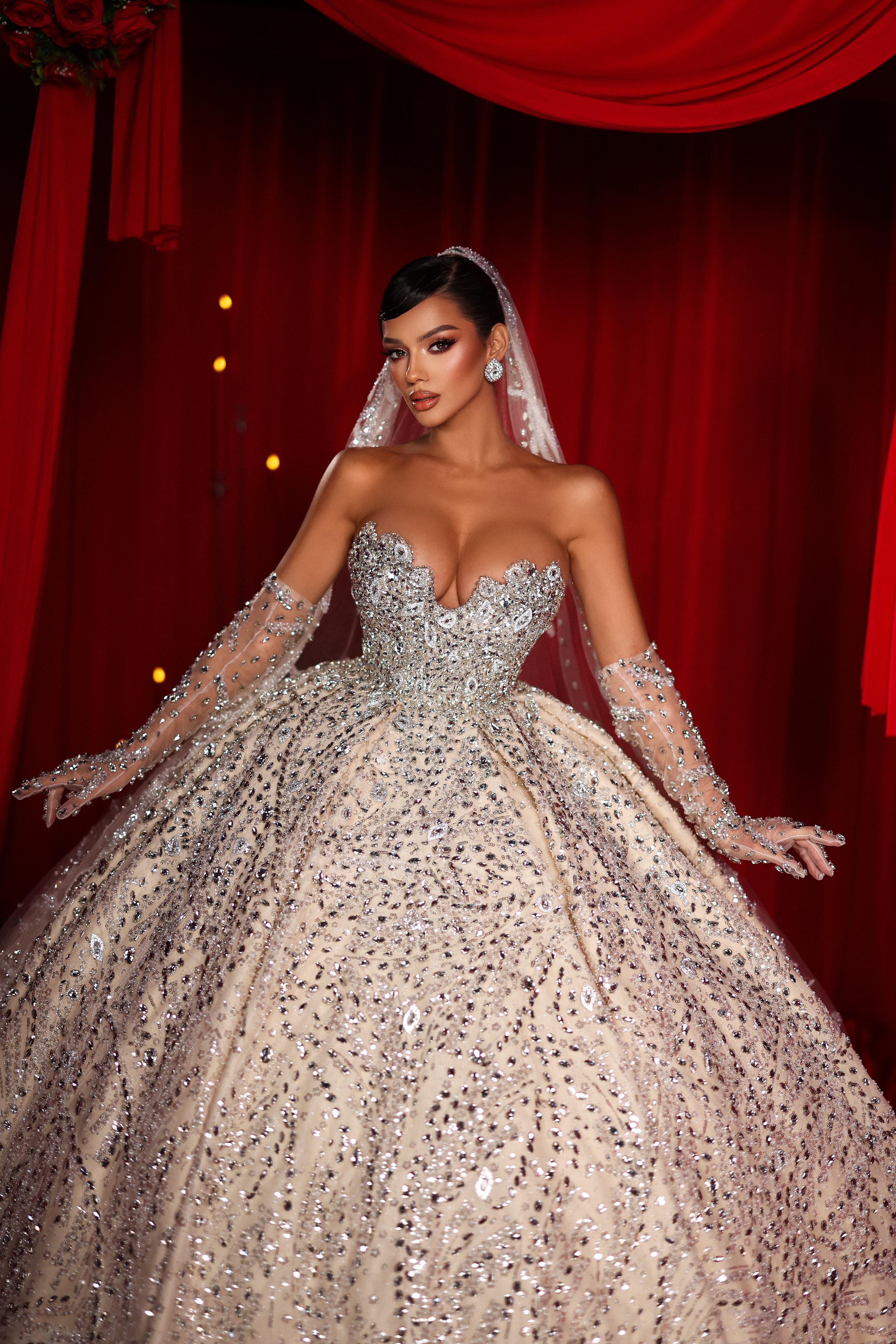 Woman in a sparkling wedding gown with a red curtain background