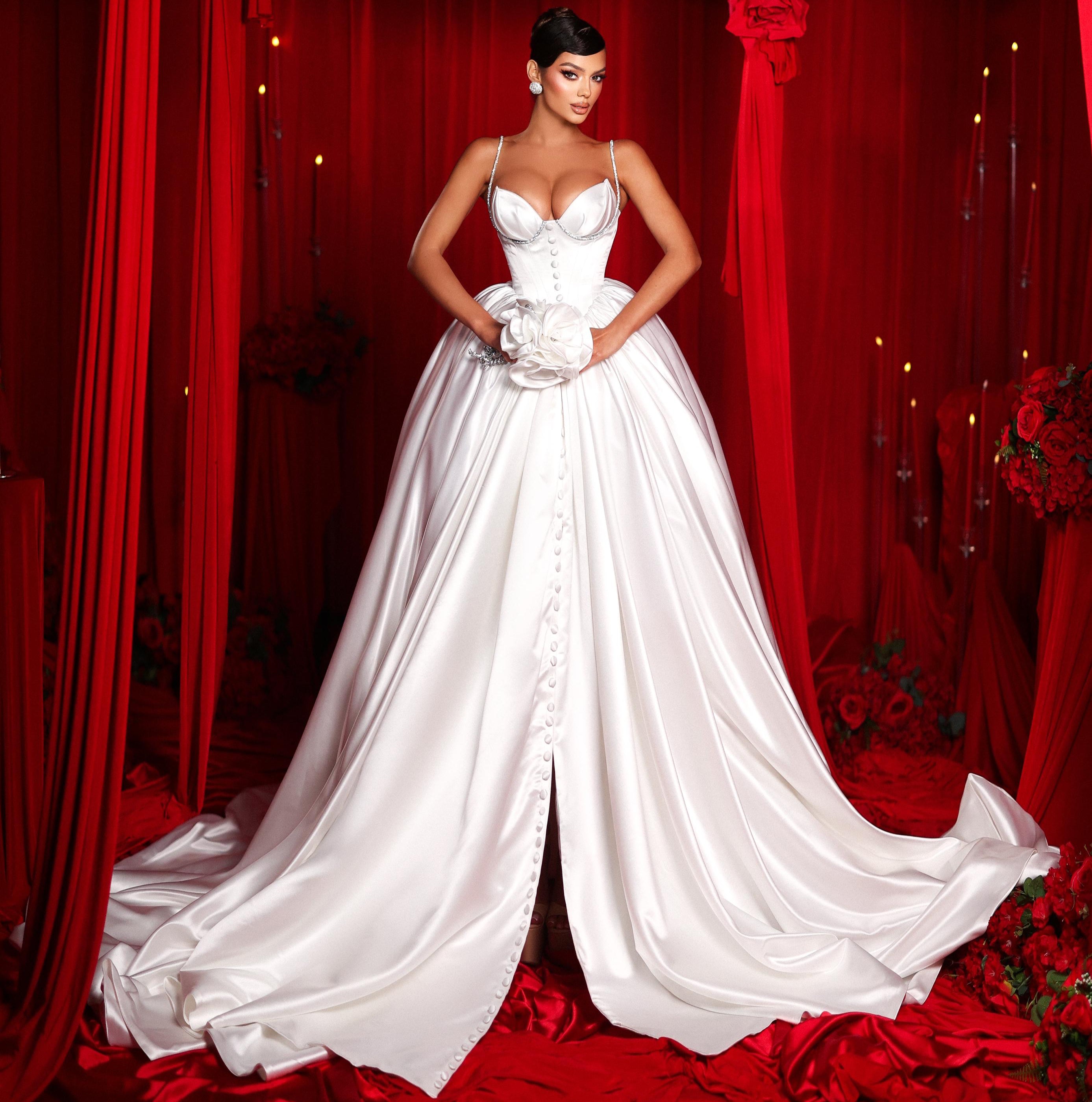 Woman in a white wedding dress standing in front of red curtains