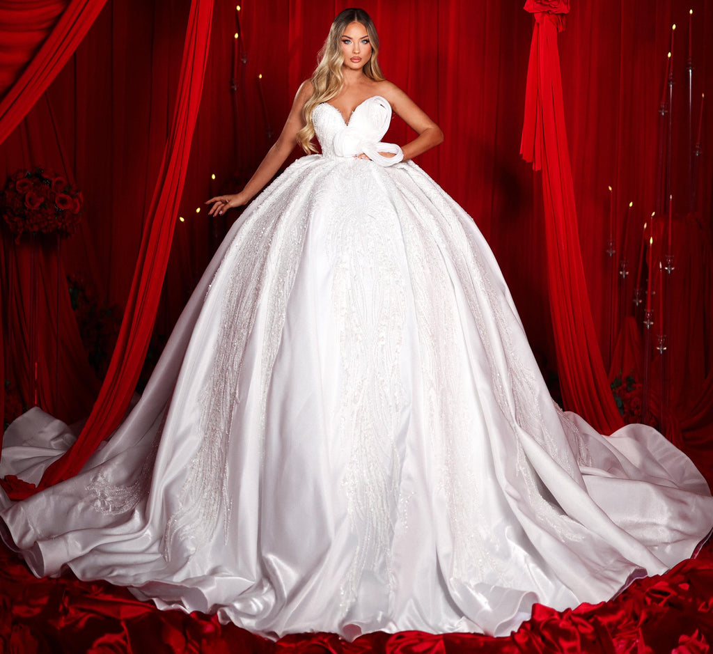 Woman in a white wedding dress standing in front of red curtains