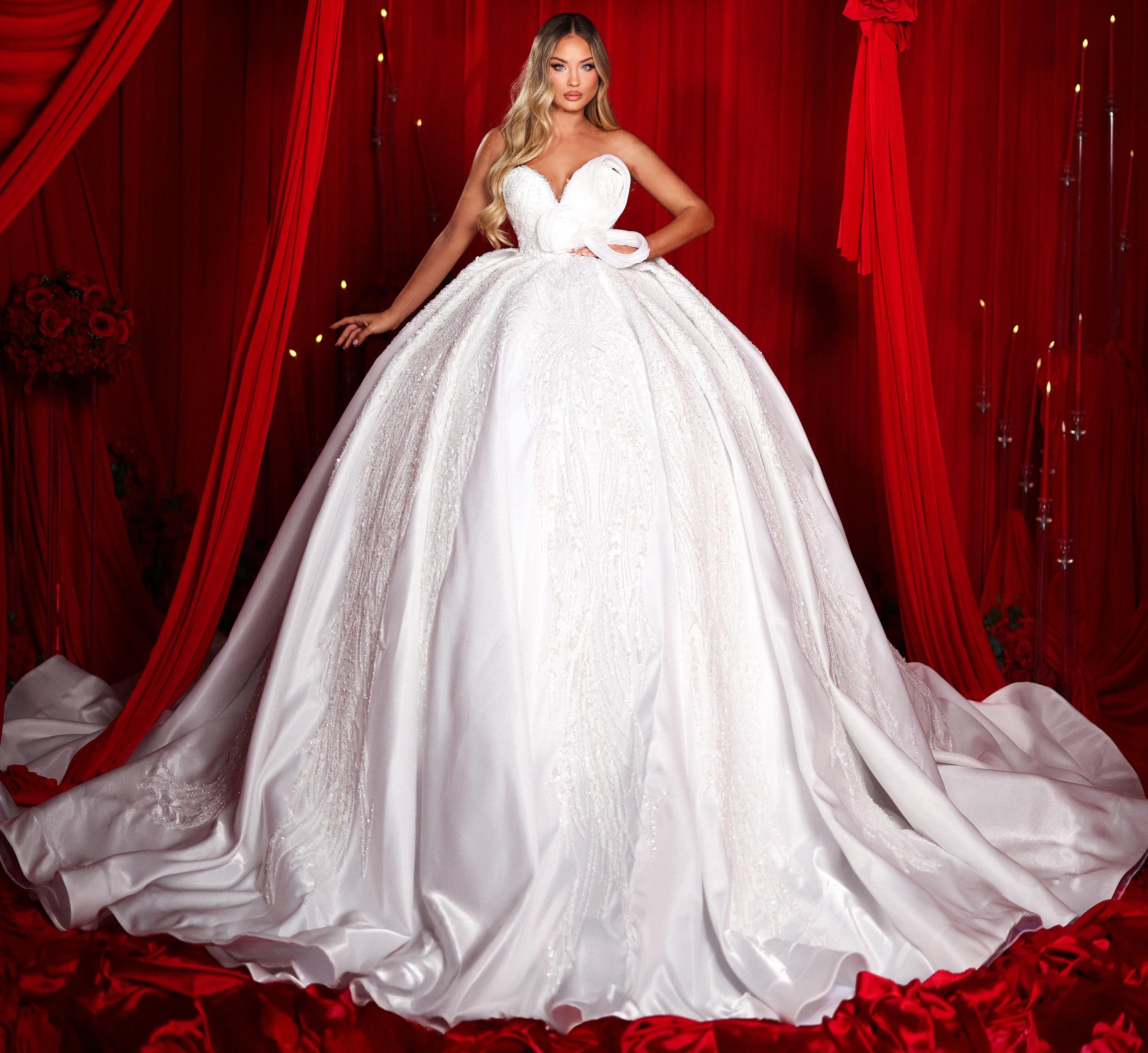 Woman in a white wedding dress standing in front of red curtains