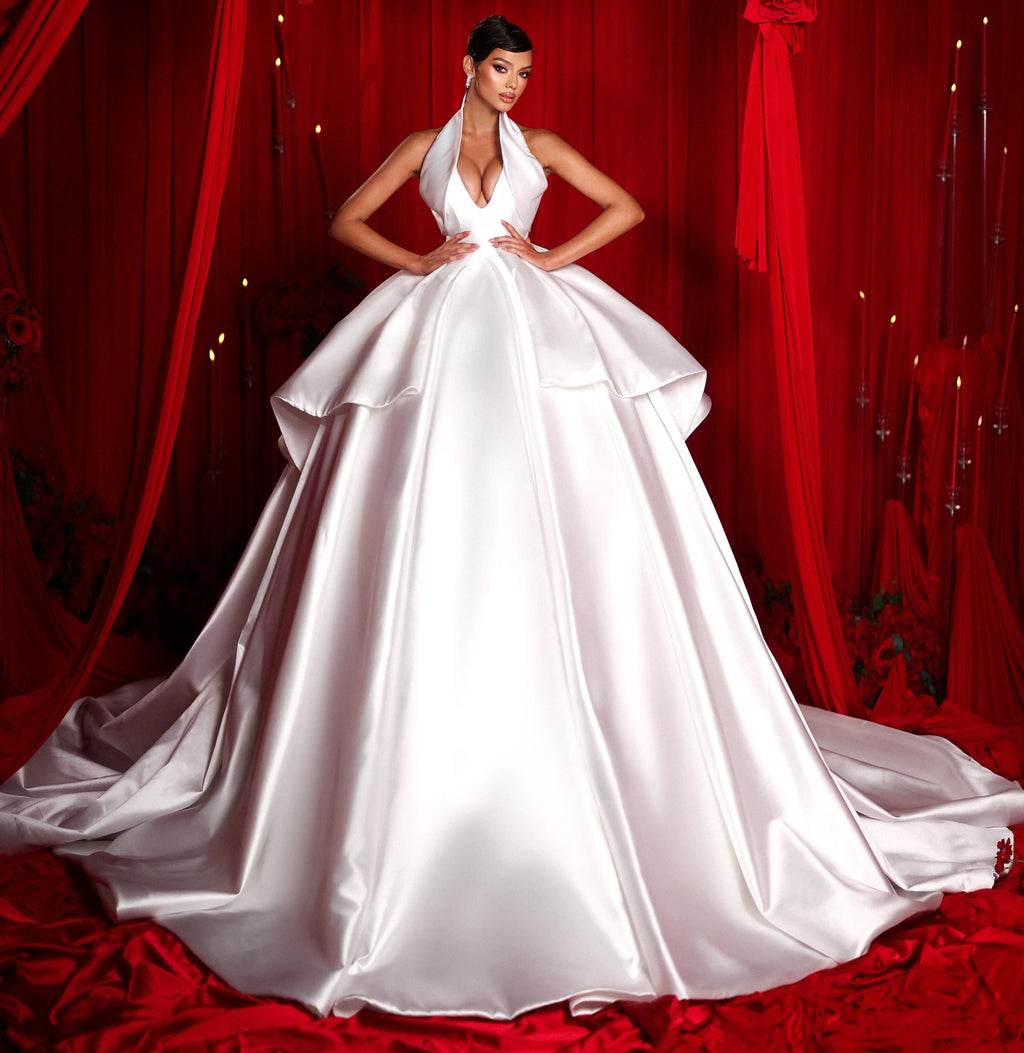 White wedding dress on a model against red curtains