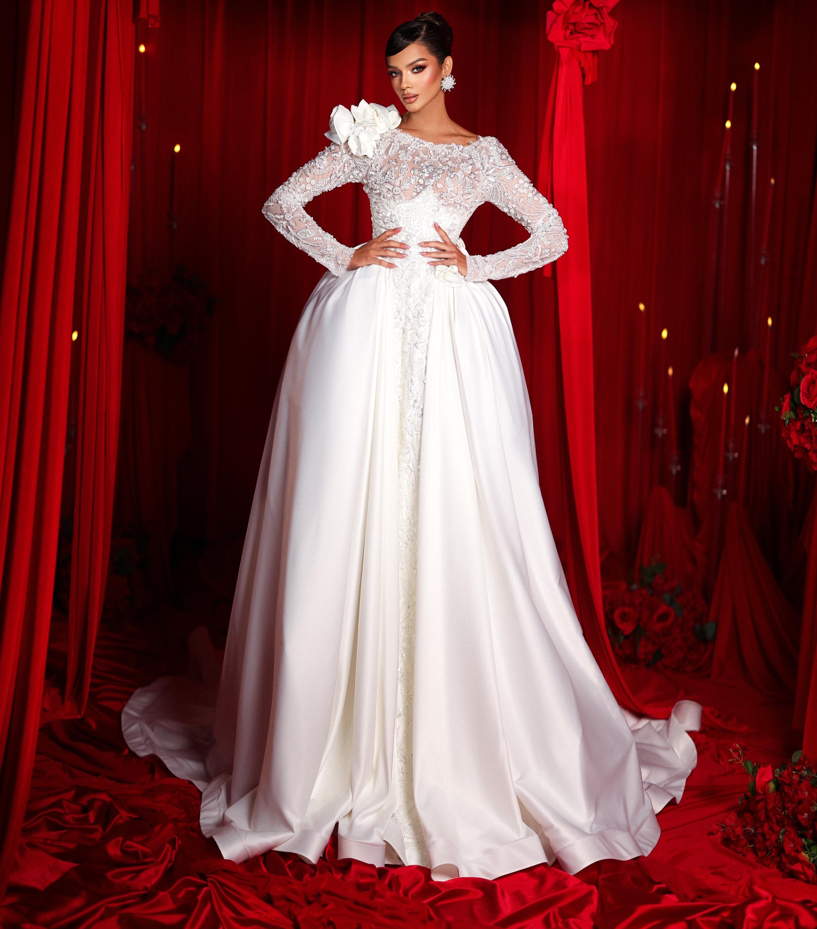 Woman in a white wedding dress standing in front of red curtains