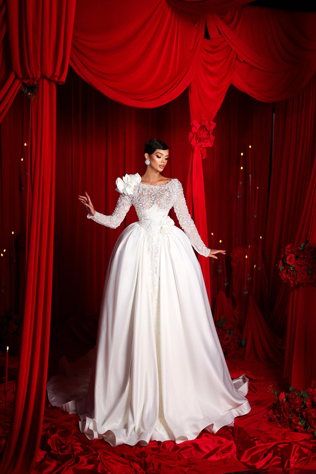 Woman in a white wedding dress standing in front of red curtains