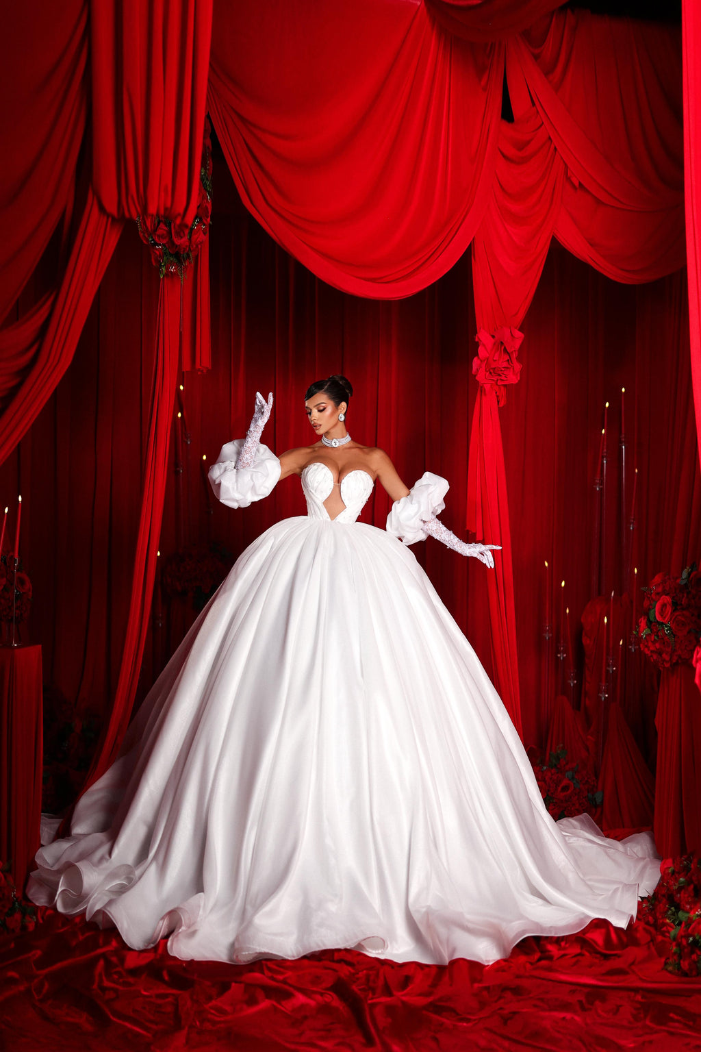 Woman in a white wedding dress standing in front of red curtains