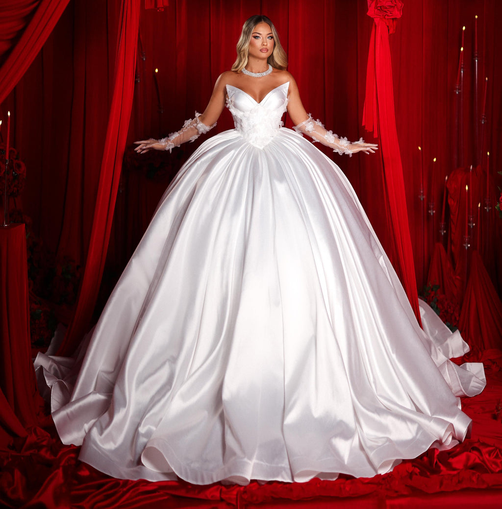 Woman in a white wedding dress standing in front of red curtains