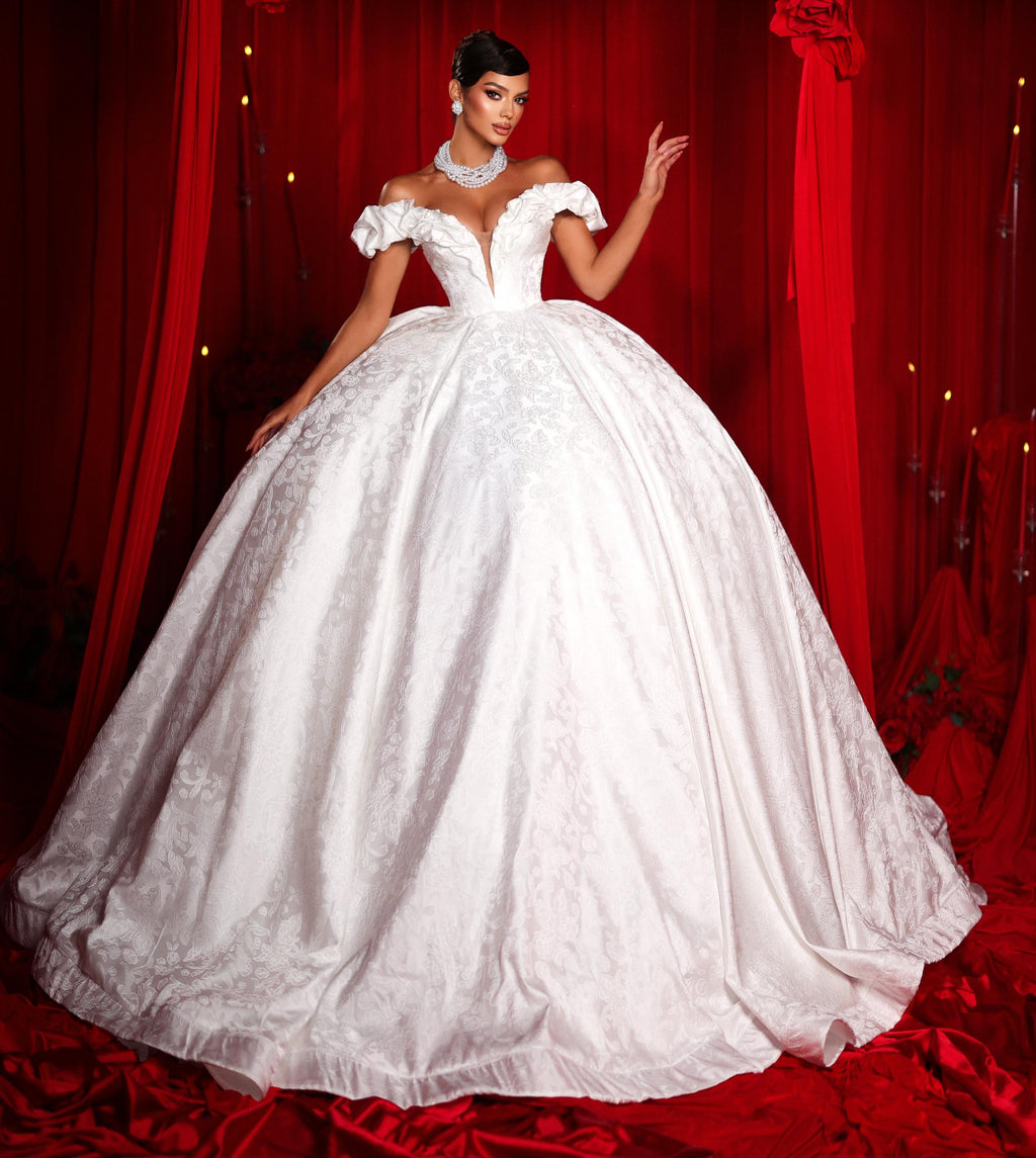 Woman in a white wedding dress standing in front of red curtains