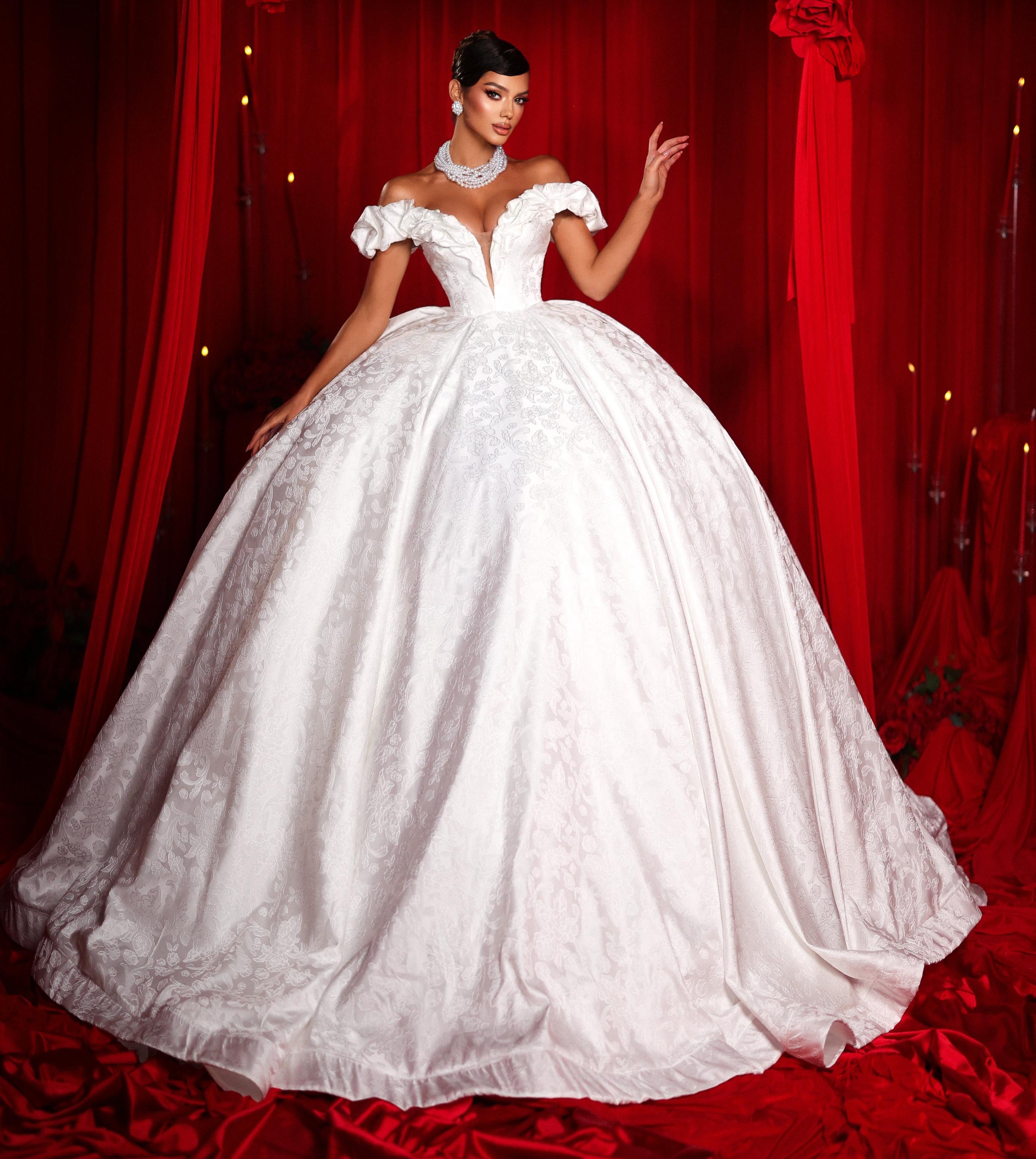 Woman in a white wedding dress standing in front of red curtains