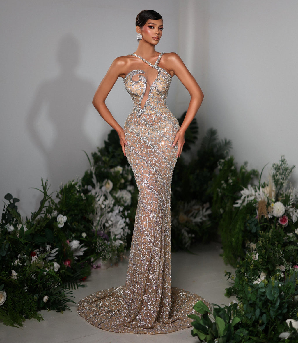 Woman in a sparkling evening gown standing against a floral decorated backdrop