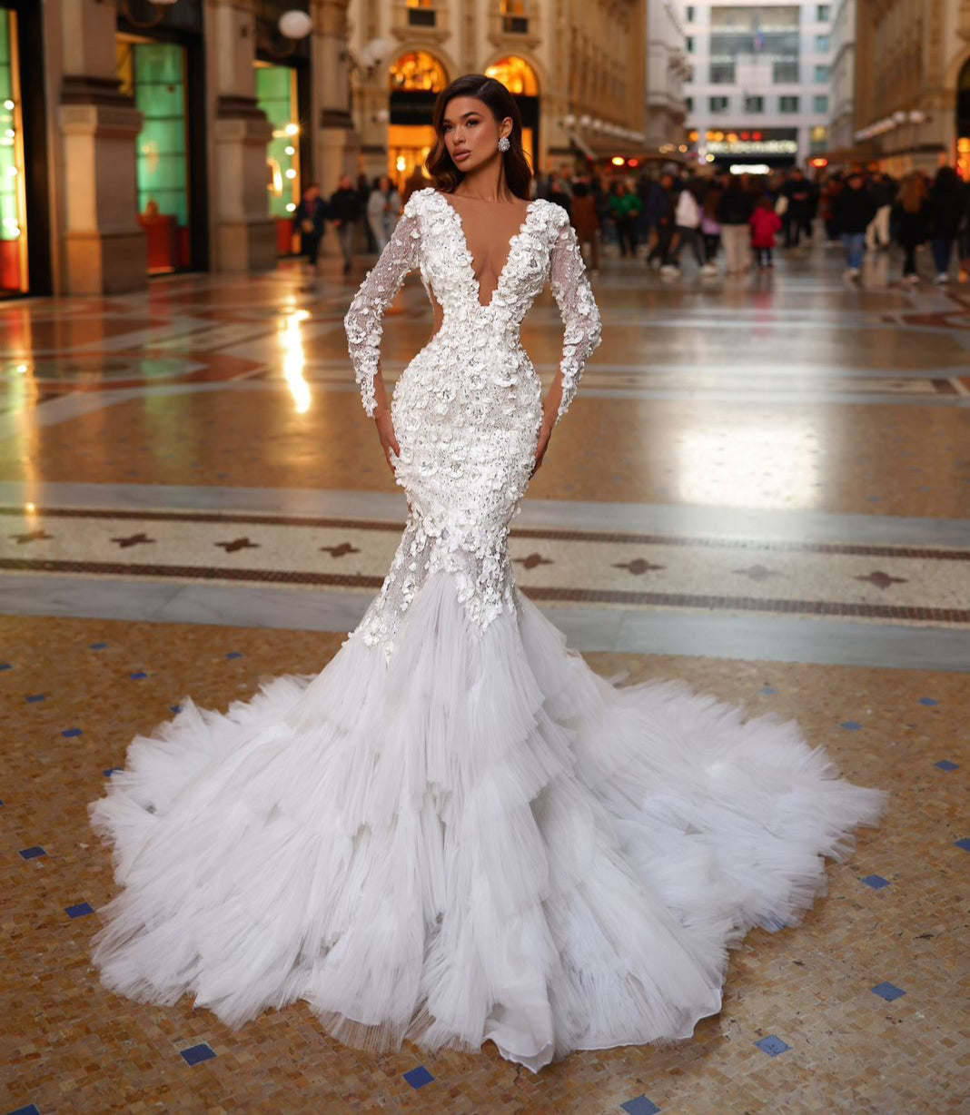 Woman in a white wedding dress standing in an elegant indoor setting with architectural details.