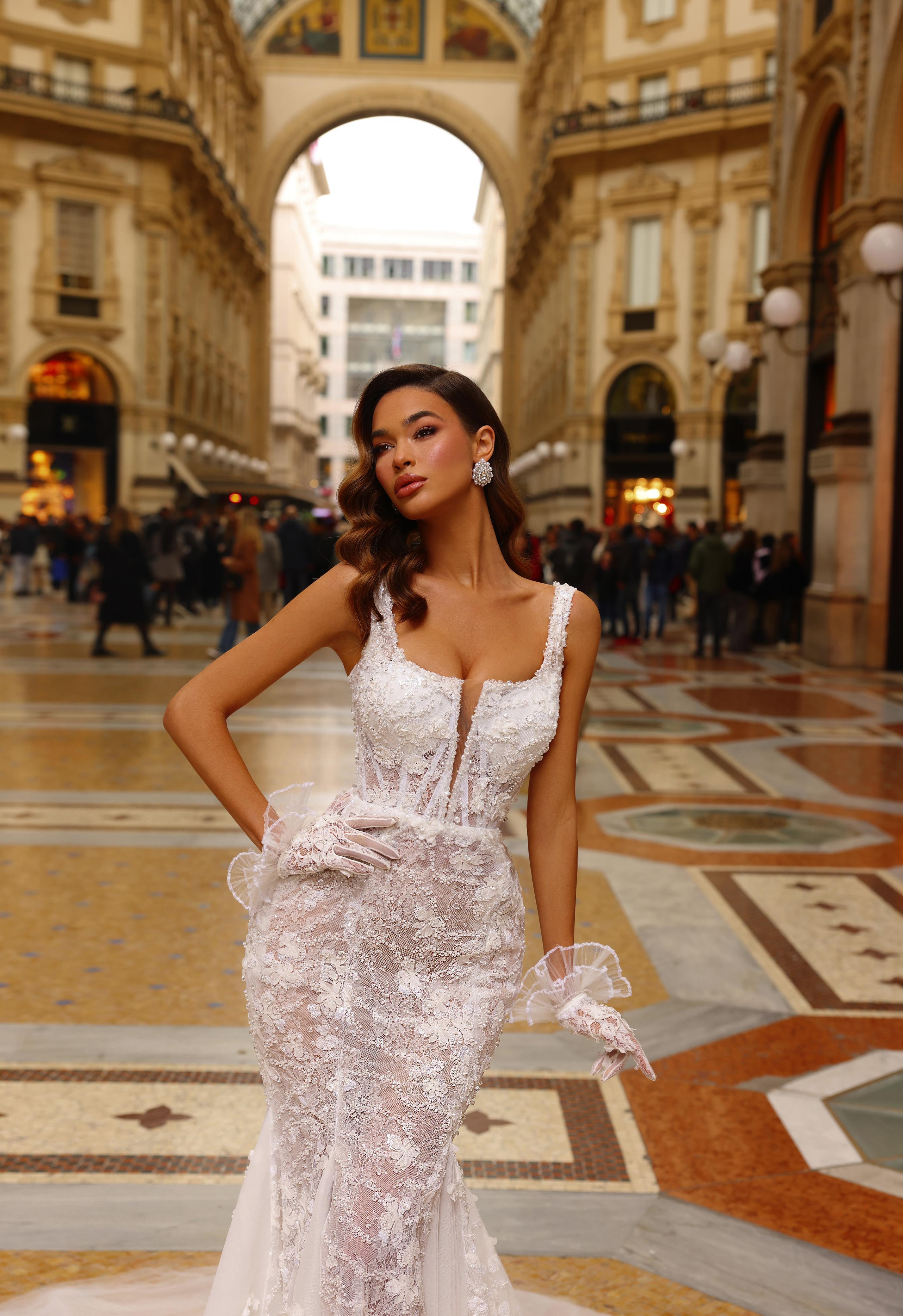 Woman in a white lace dress standing in an elegant indoor shopping arcade.
