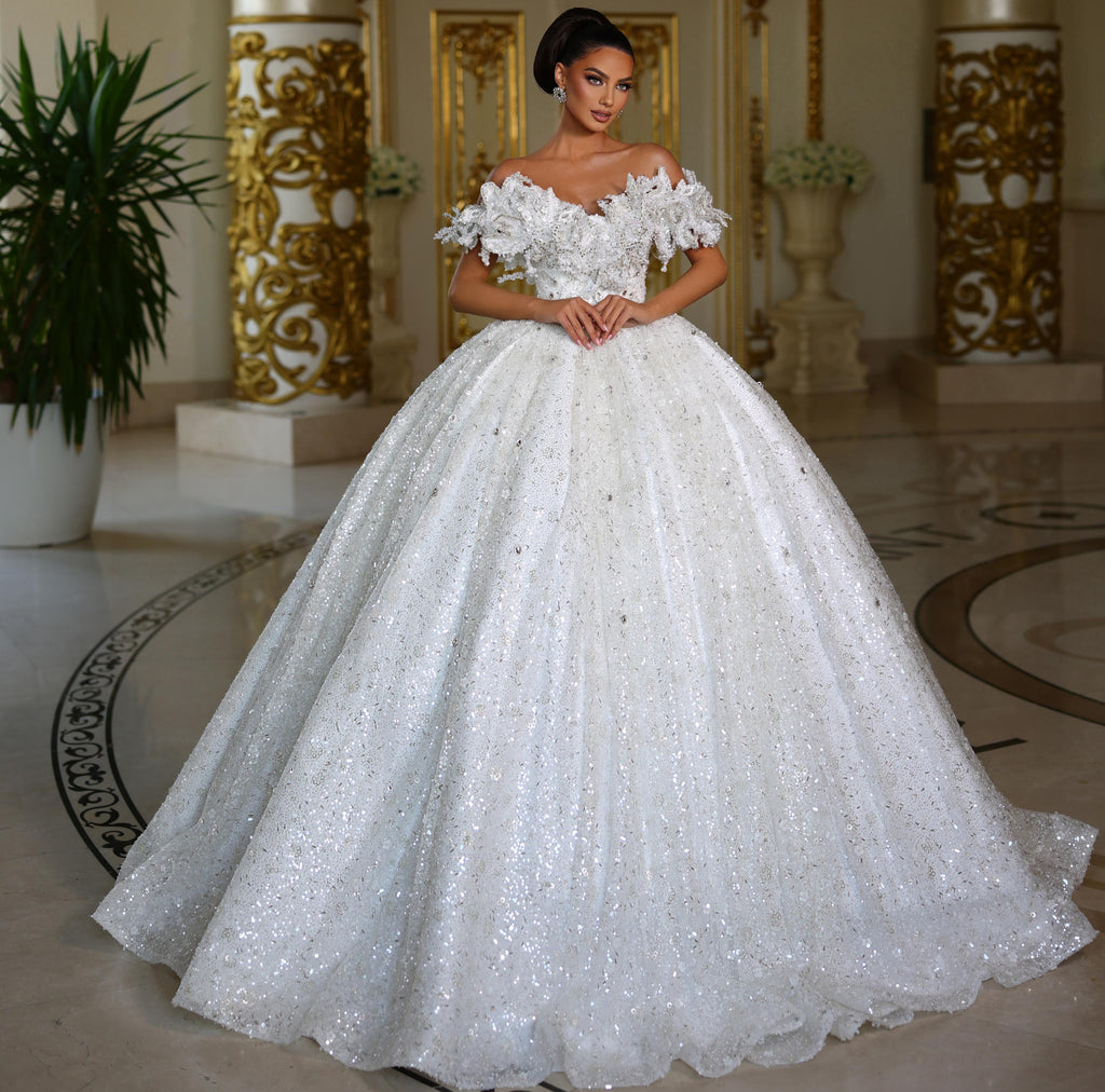 Woman in a white wedding dress standing in an elegant interior setting.