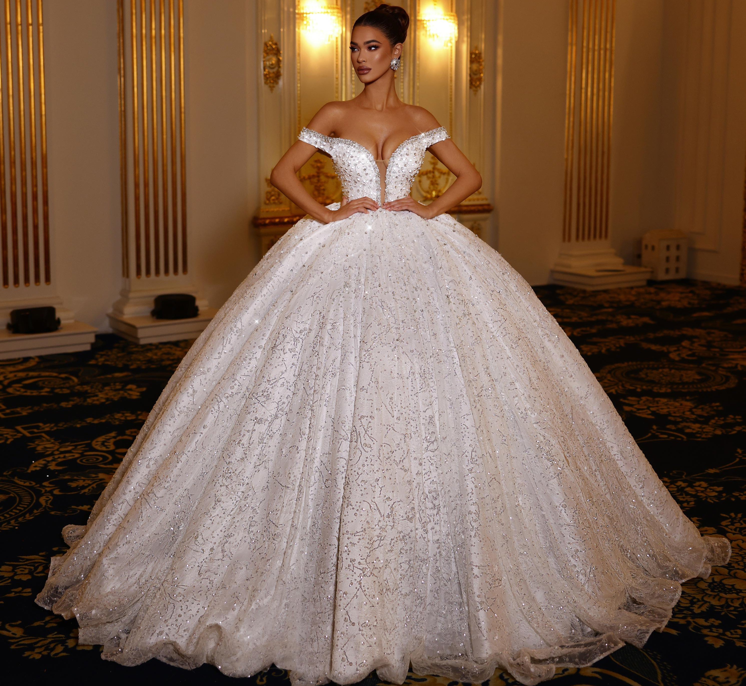 Woman in a white wedding dress standing in an elegant room with gold accents.