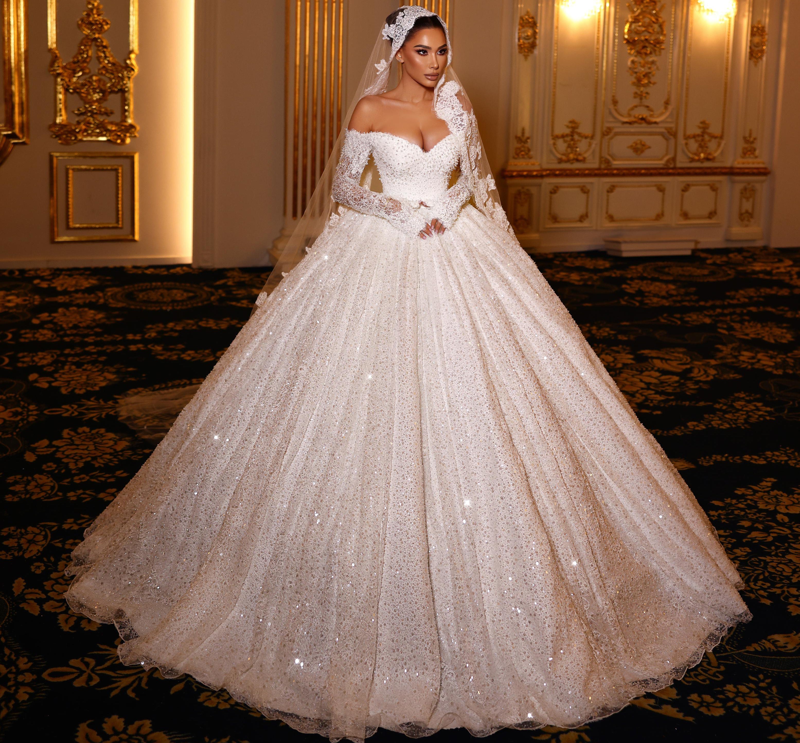 Woman in a white wedding dress standing in an ornate room with gold decorations.