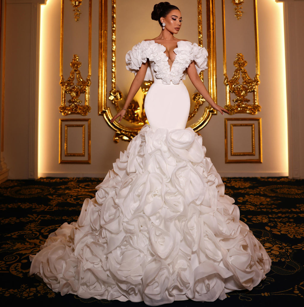 Woman in a white wedding dress standing in front of ornate gold mirrors.