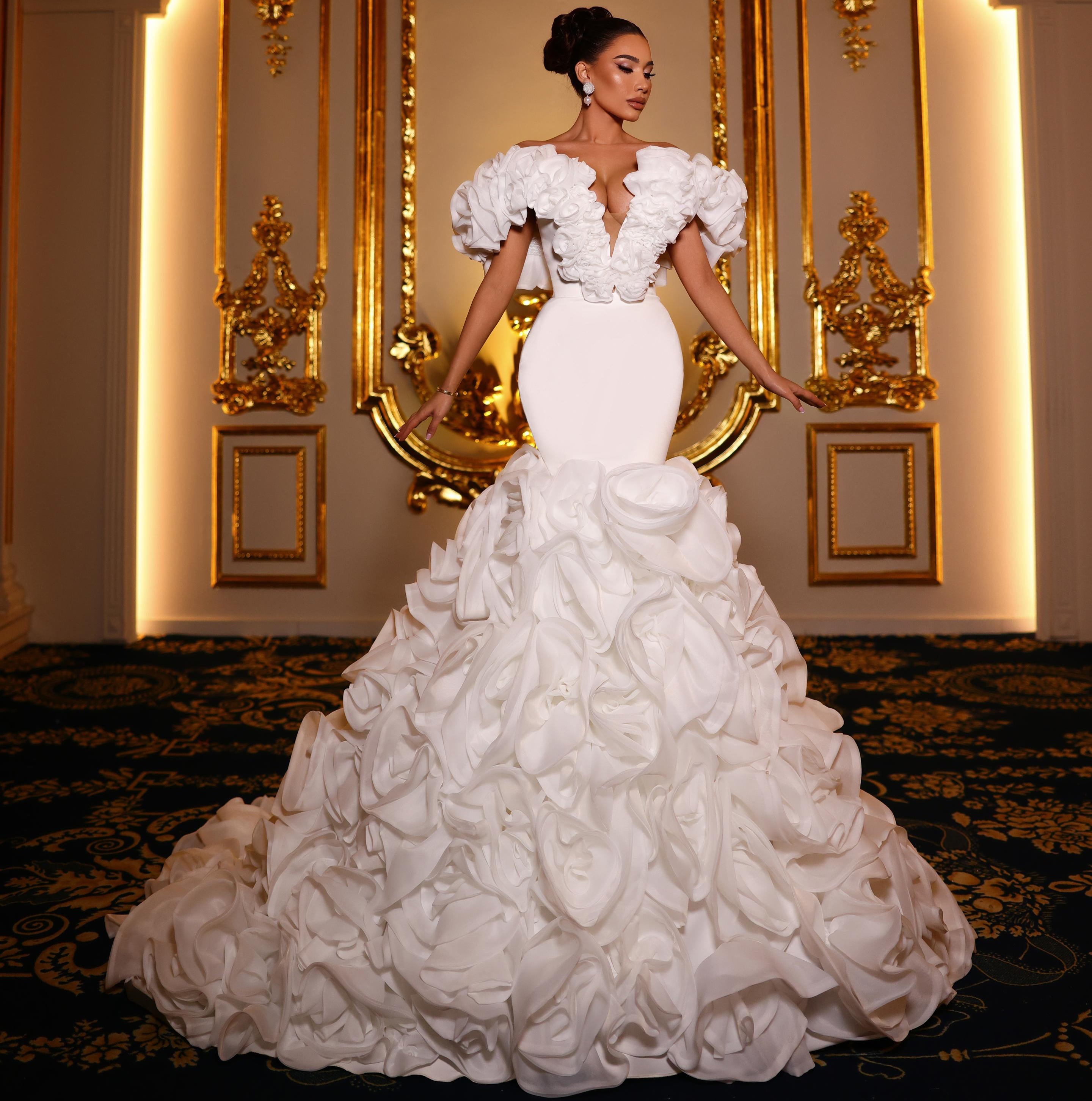 Woman in a white wedding dress standing in front of ornate gold mirrors.