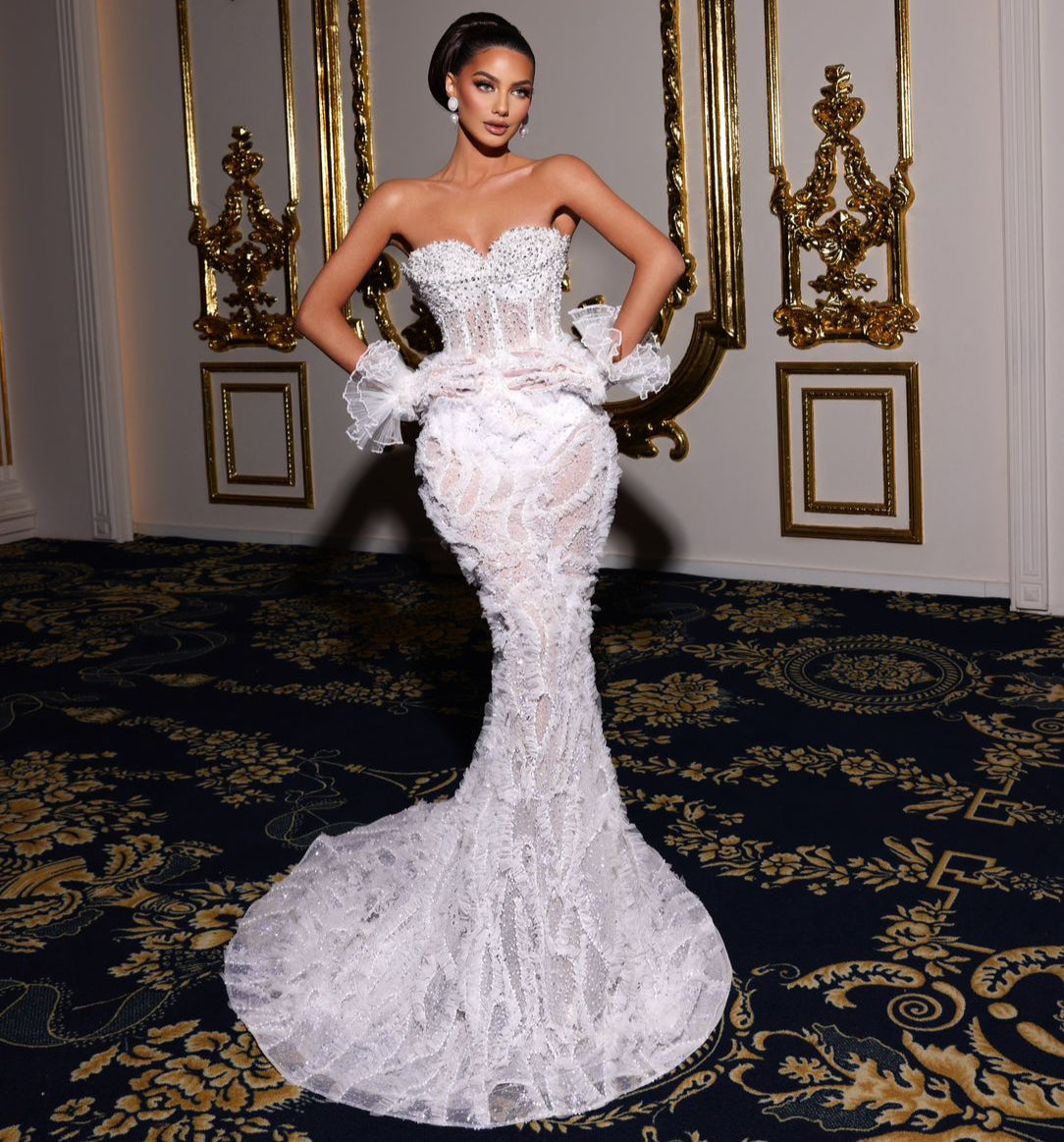 Woman in a white strapless gown standing in an ornate room with gold decorations.