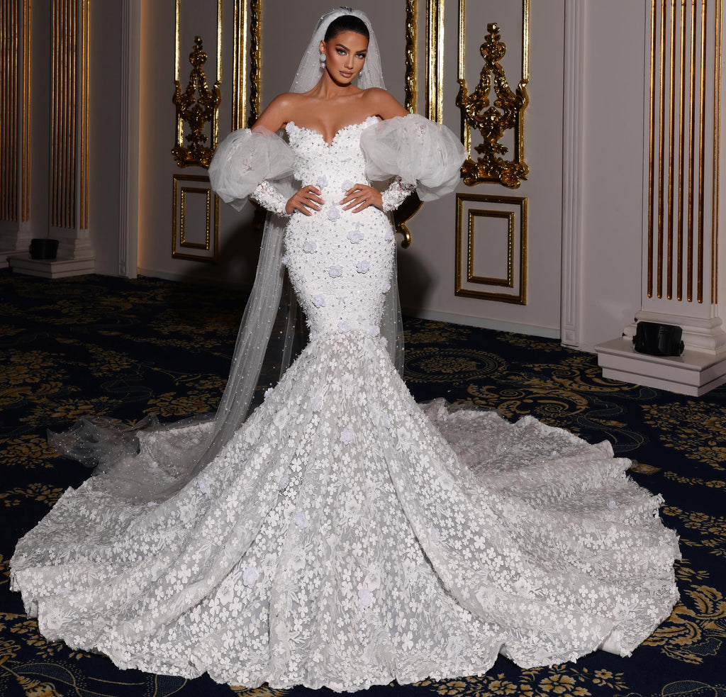 Woman in a white wedding dress with a long train in an ornate room.