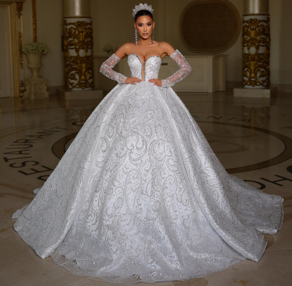 Woman in a white wedding dress standing in an elegant indoor setting.