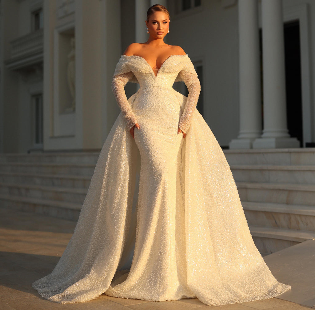 Woman in a white wedding dress standing in front of an elegant building.
