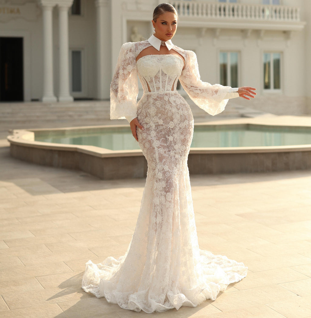 Woman in a white lace dress standing in front of an elegant building with a pool.