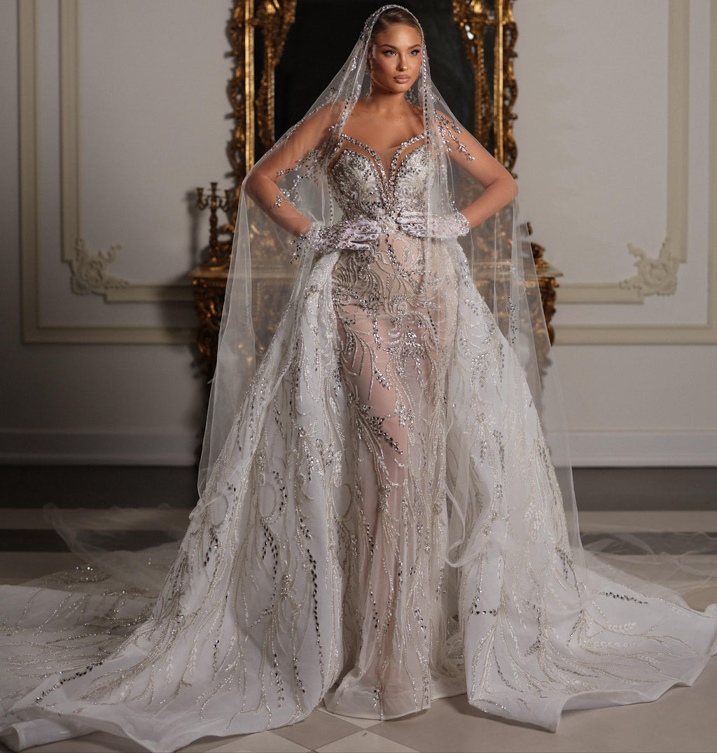 Woman in a sparkling silver wedding dress with a long train in a decorated room.