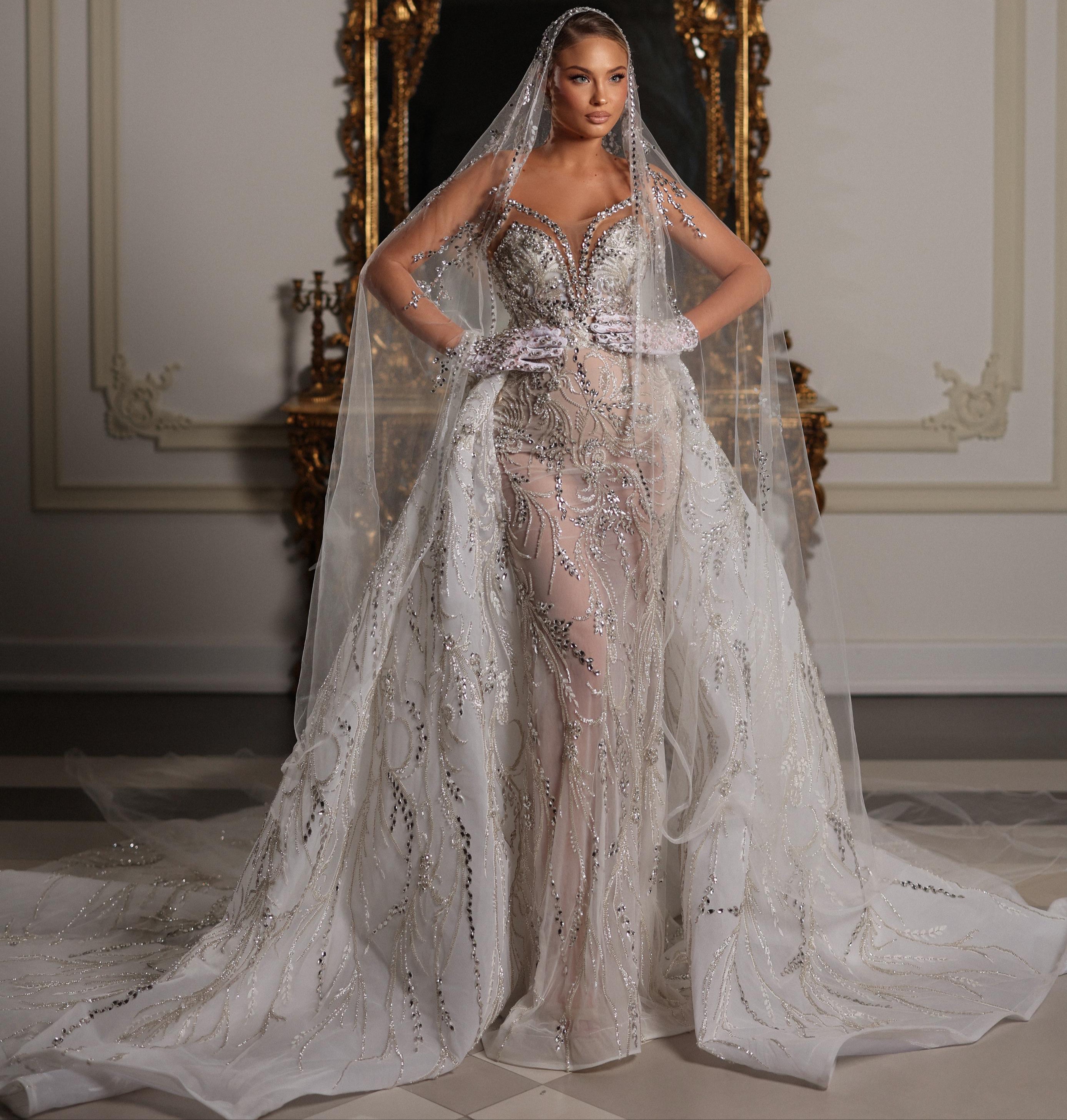 Woman in a sparkling silver wedding dress with a long train in a decorated room.