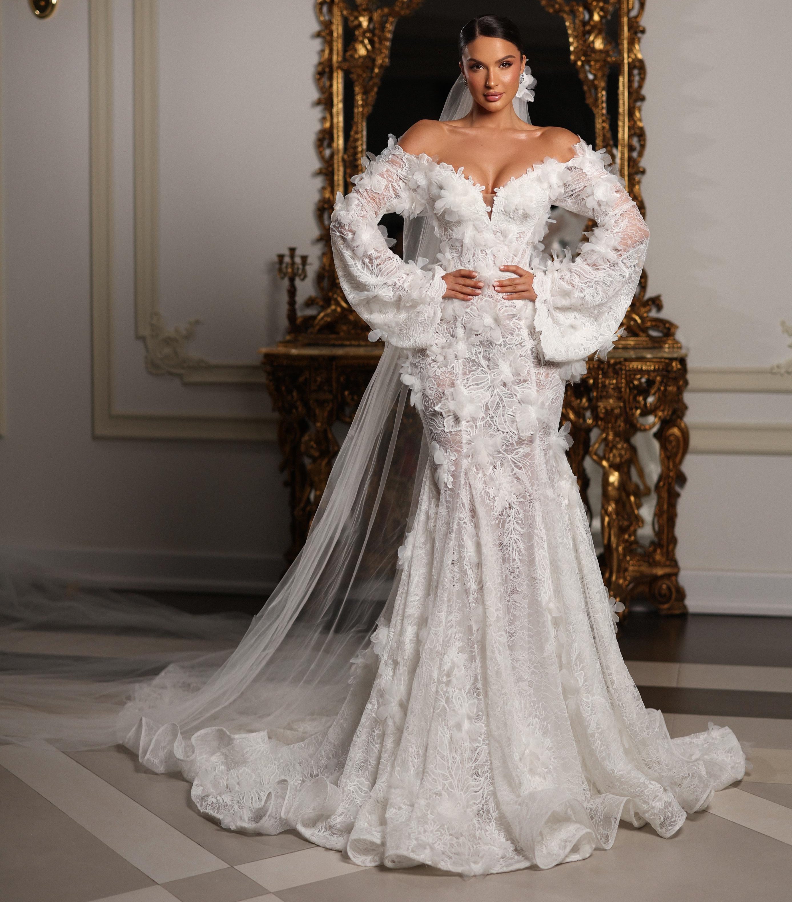 Woman in a white wedding dress standing in a room with ornate decor.