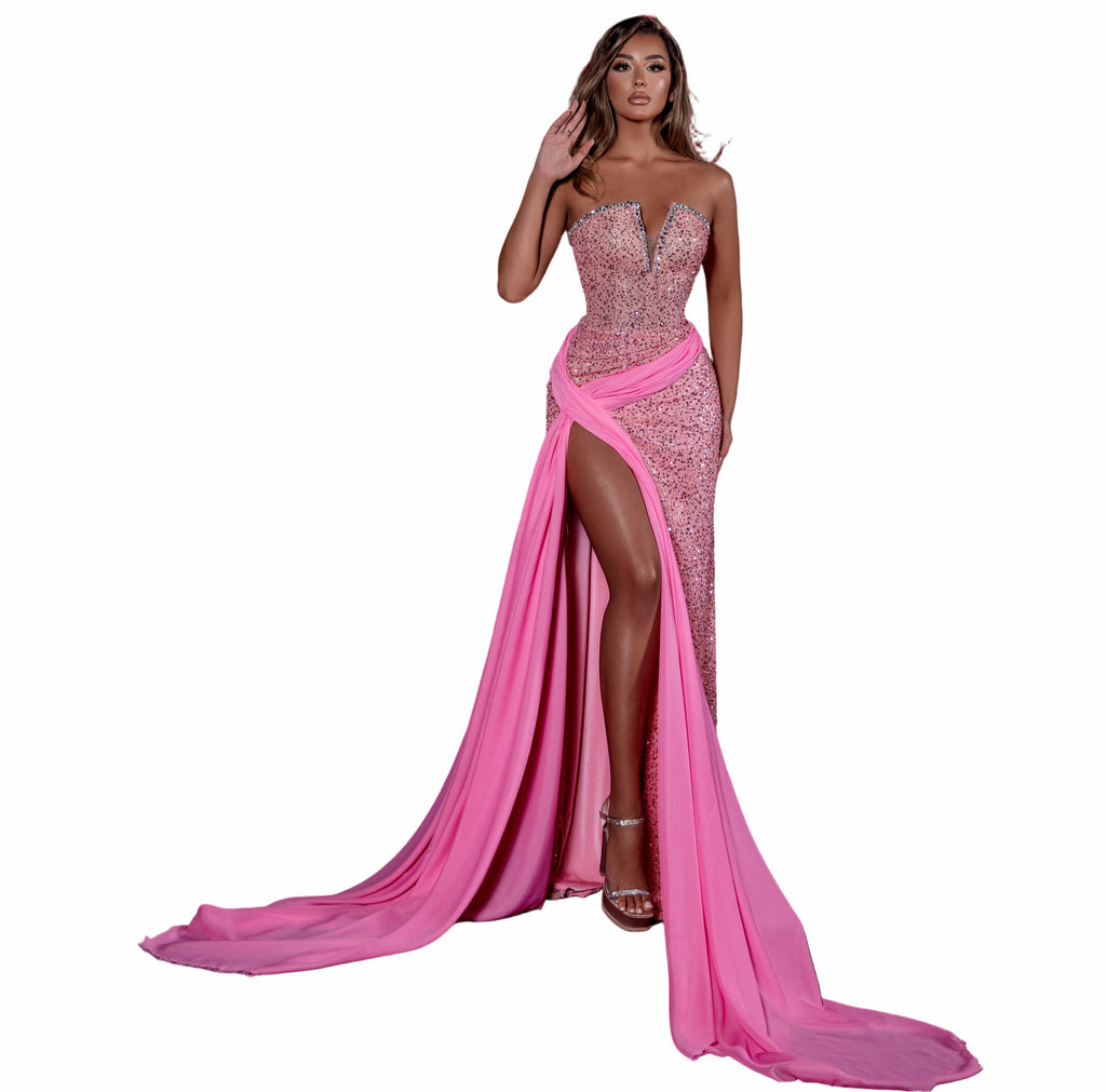 Woman in a pink evening gown with a high slit standing in an empty theater.