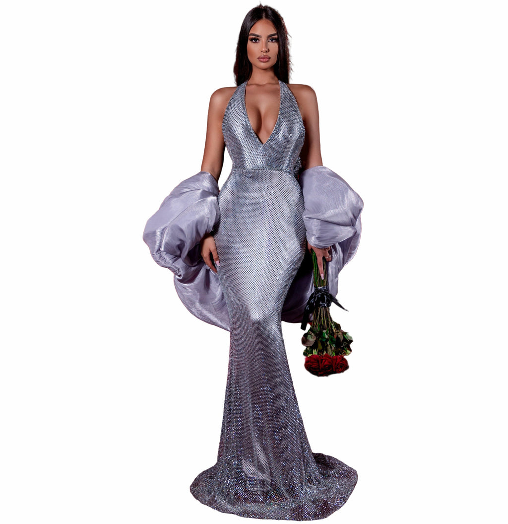 Woman in a silver gown standing in an empty movie theater with red seats.