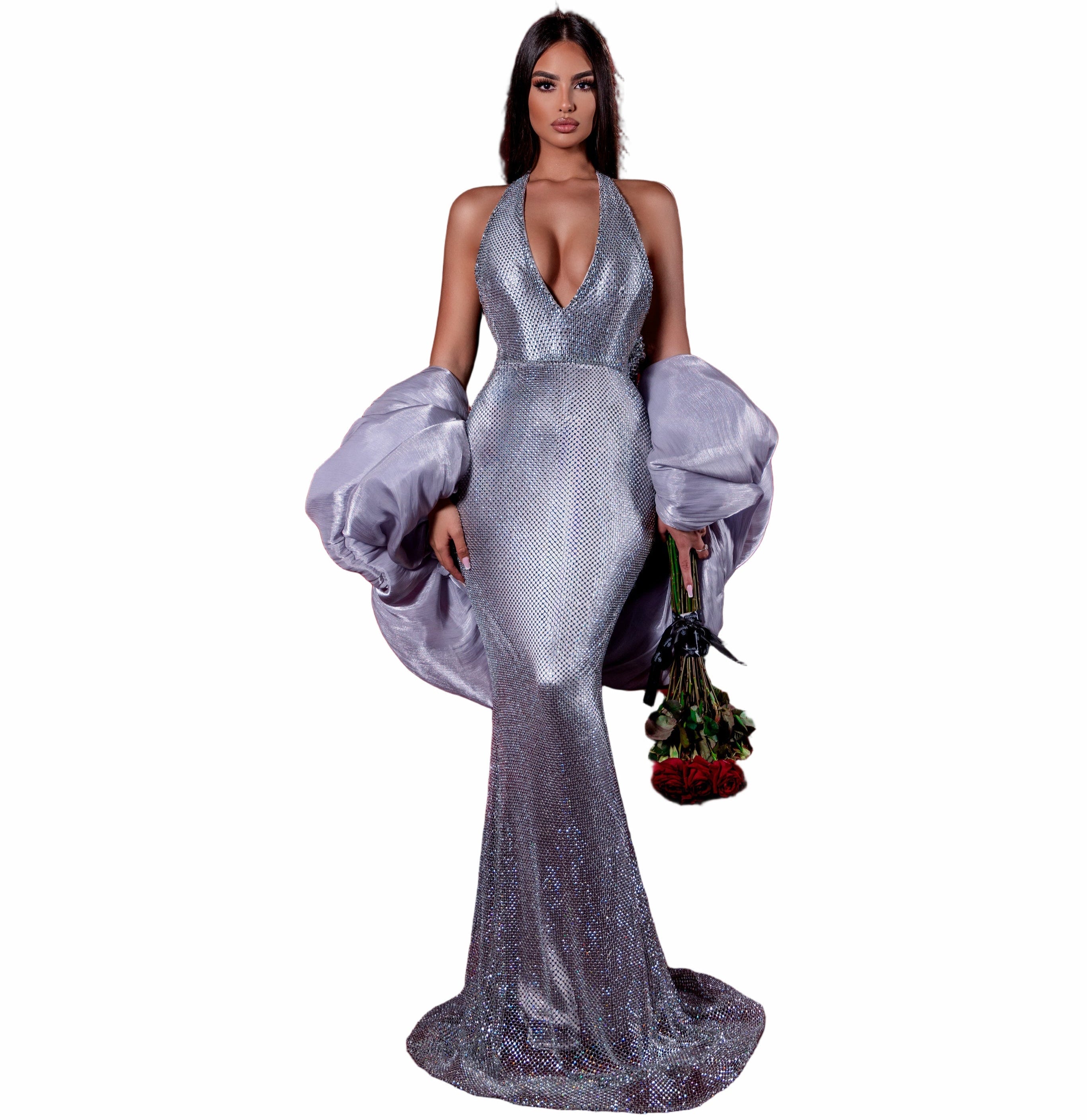 Woman in a silver gown standing in an empty movie theater with red seats.