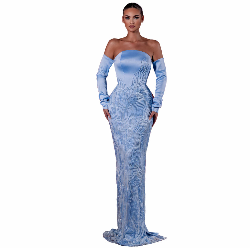 Woman in a blue evening gown standing in an empty theater with red seats.