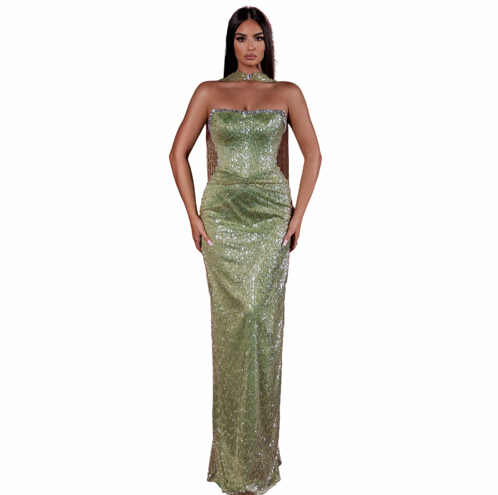 Woman in a green sequined dress standing in an empty theater with red seats.