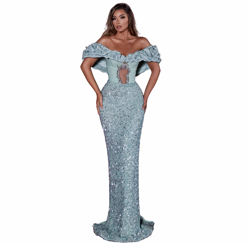 Woman in a silver off-shoulder gown standing in an empty theater with red seats.